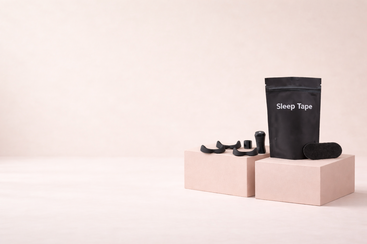 Black sleep tape packaging with earplugs on pink blocks against a beige background