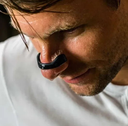 Black curved internal nasal airway dilator worn on the man's nose bridge against a white background.